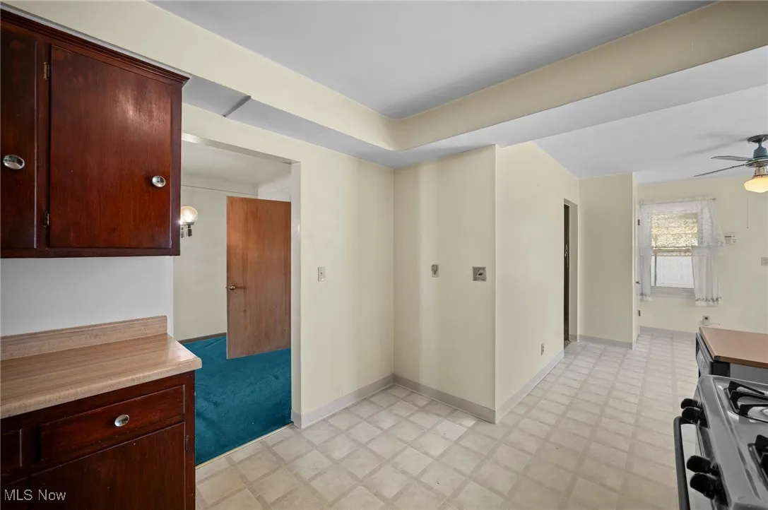 Kitchen featuring range with gas stovetop, light floors, ceiling fan, and light countertops