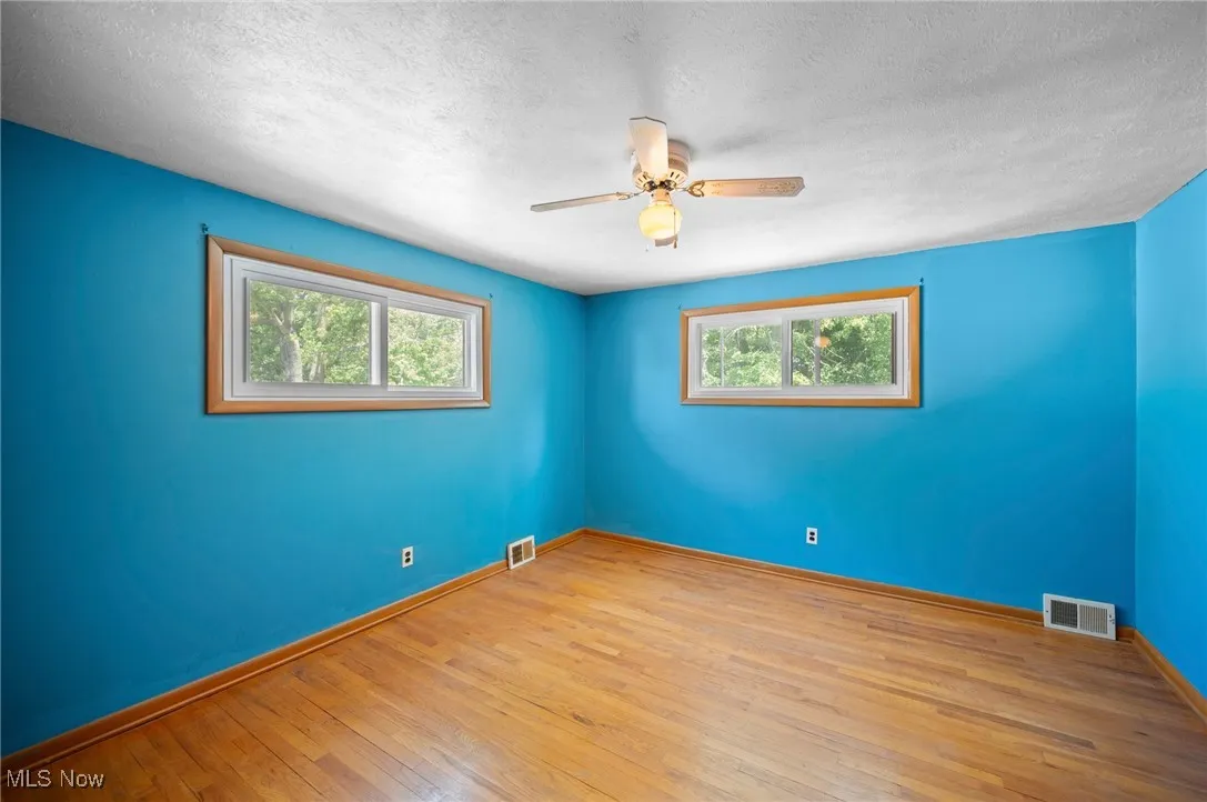 Bedroom with healthy amount of natural light, wood-type flooring, and ceiling fan