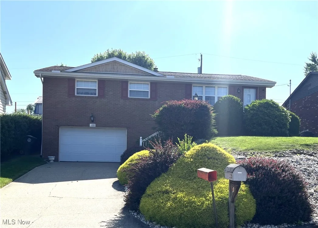 View of front of home with a garage, driveway, and brick siding