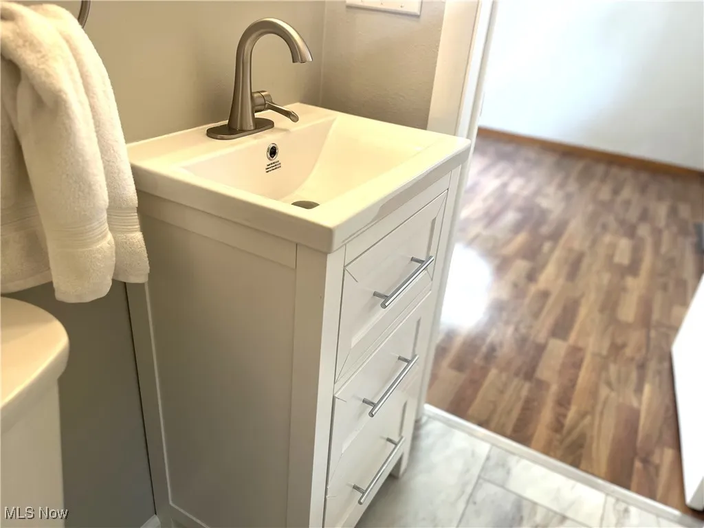 Half bathroom with vanity and wood finished floors