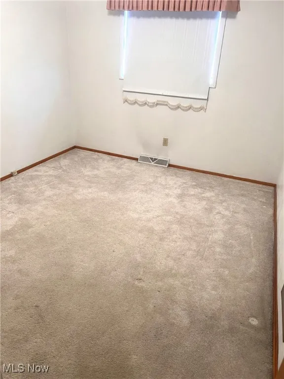 Carpeted spare room featuring baseboards