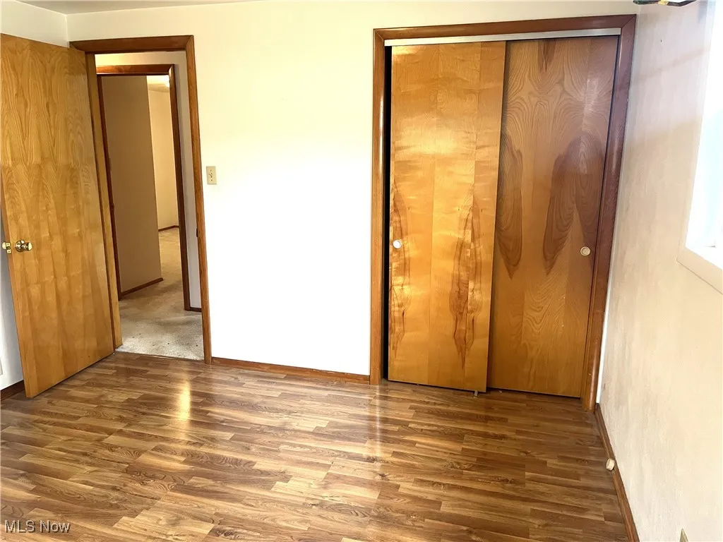 Unfurnished bedroom with wood finished floors and a closet