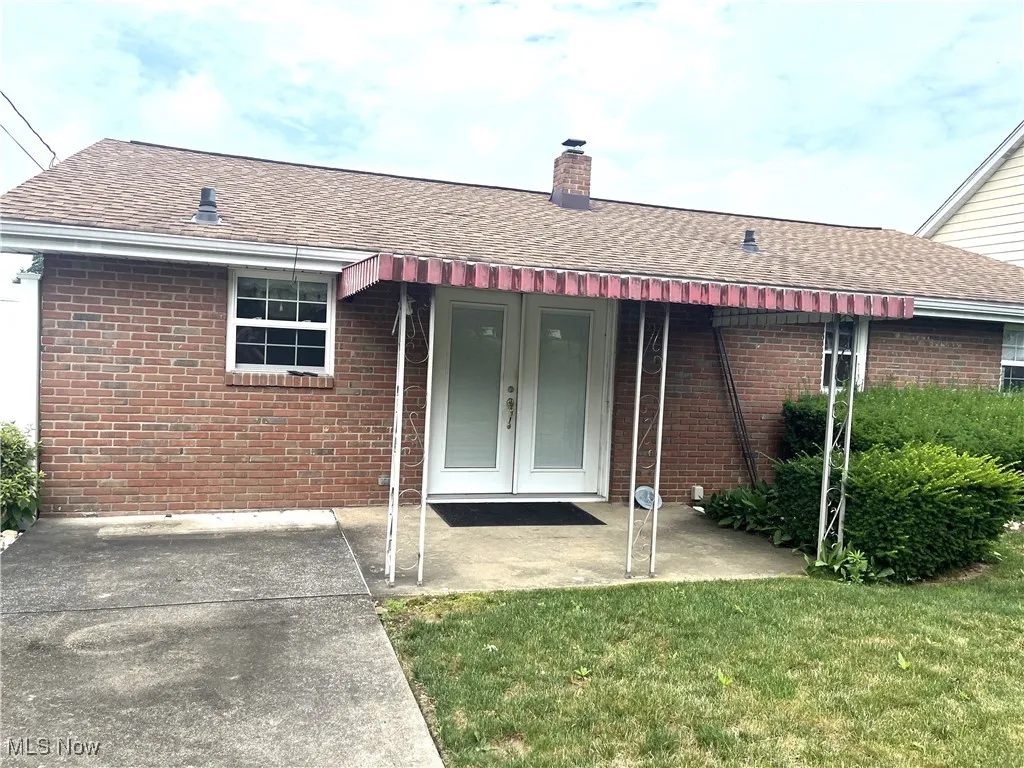 Rear view of house featuring french doors, brick siding, roof with shingles, and a chimney