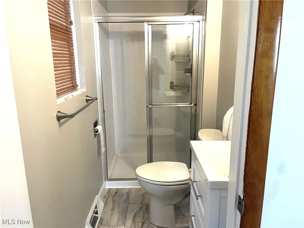 Full bathroom with vanity, a shower stall, and marble finish flooring
