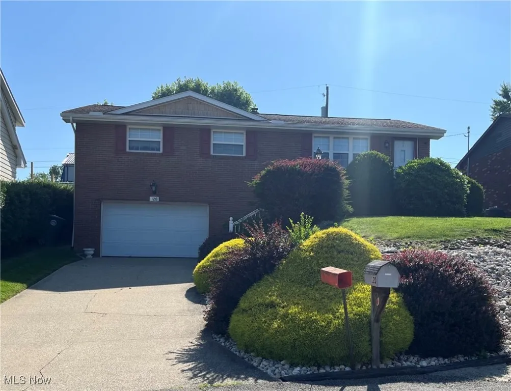 View of front of property featuring an attached garage, brick siding, and driveway