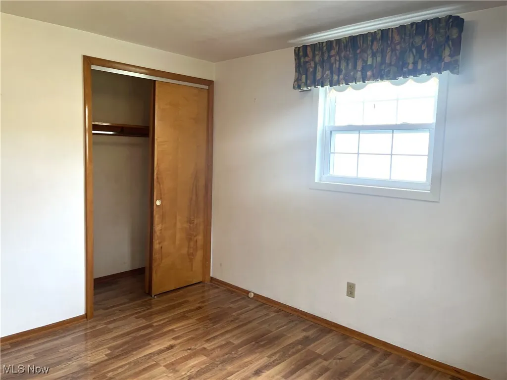 Unfurnished bedroom featuring wood finished floors and a closet