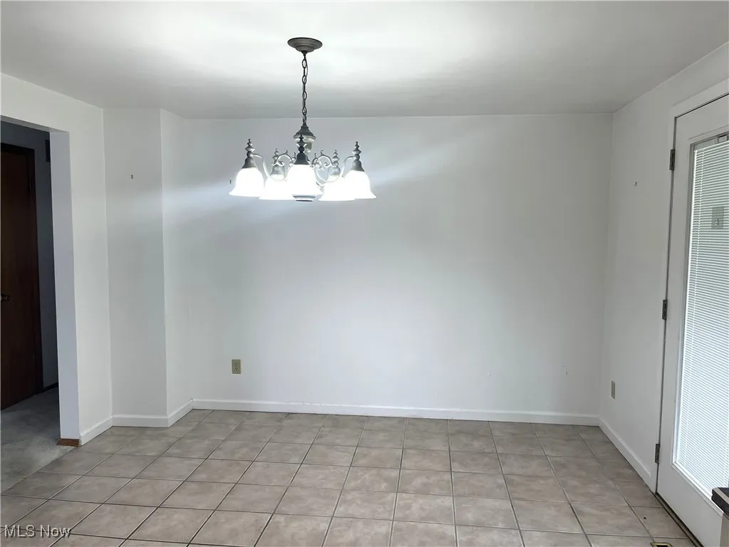 Spare room with a chandelier and baseboards