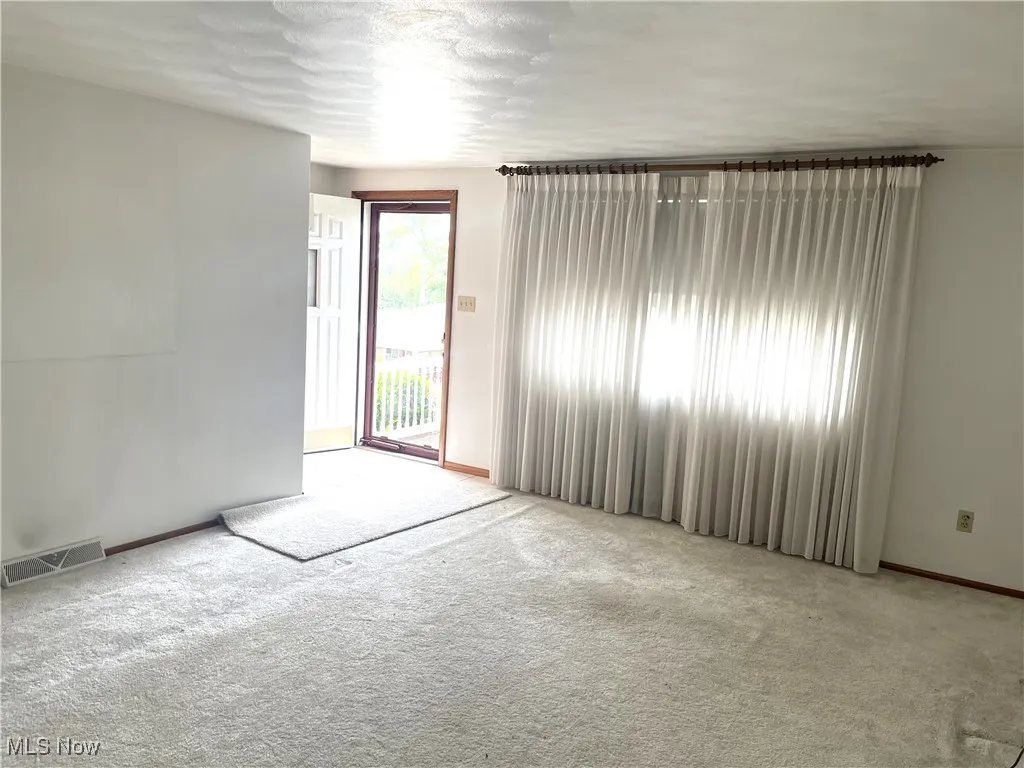 Carpeted spare room with baseboards