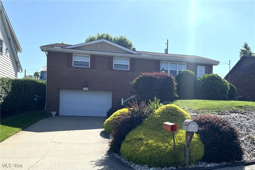 View of front of house with an attached garage, brick siding, and driveway