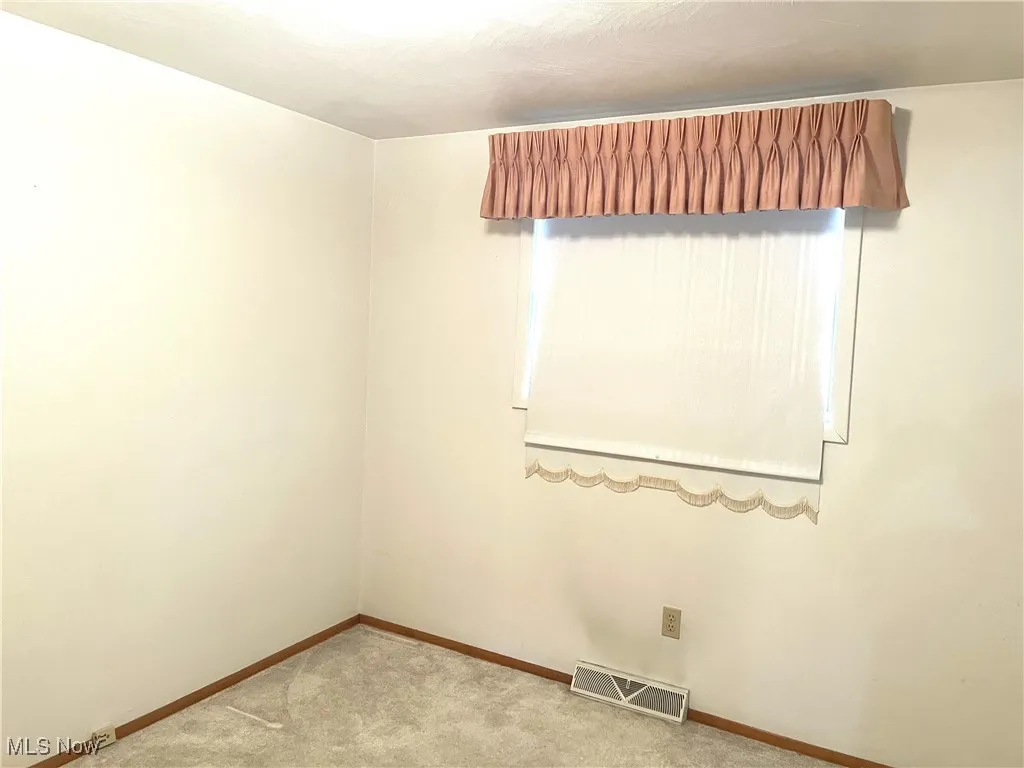 Empty room featuring carpet flooring and baseboards