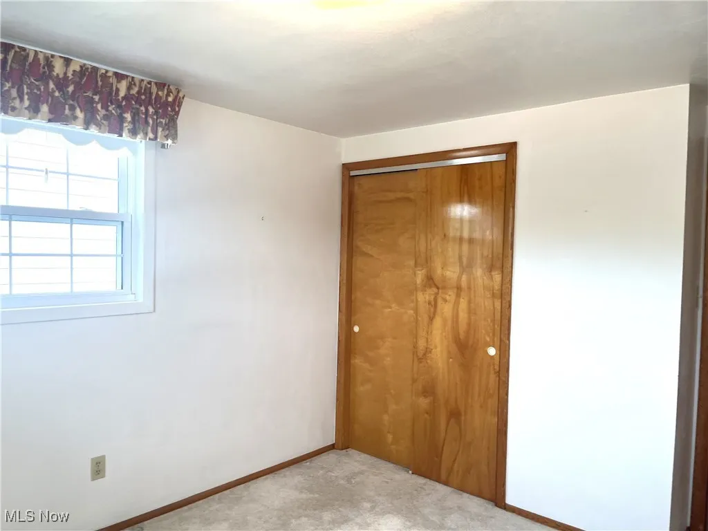 Spare room featuring light colored carpet and baseboards