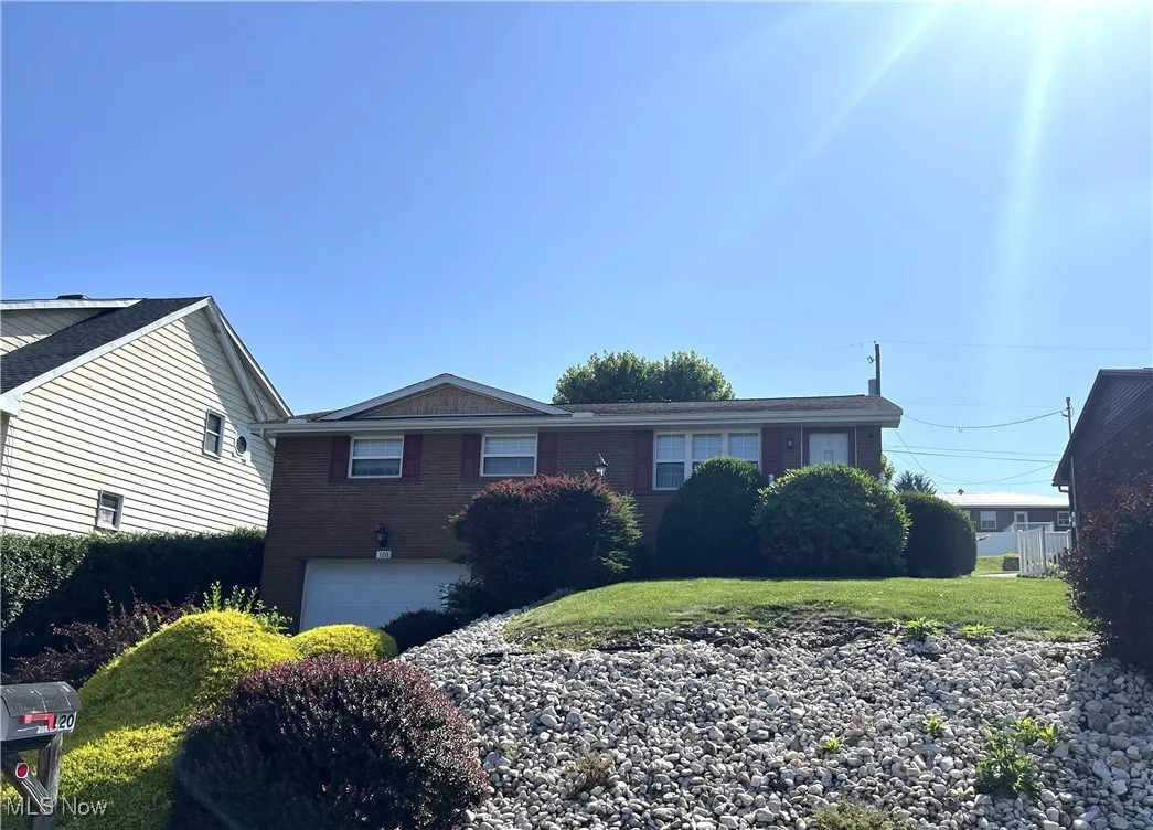 View of front of home featuring a garage, brick siding, and a front lawn