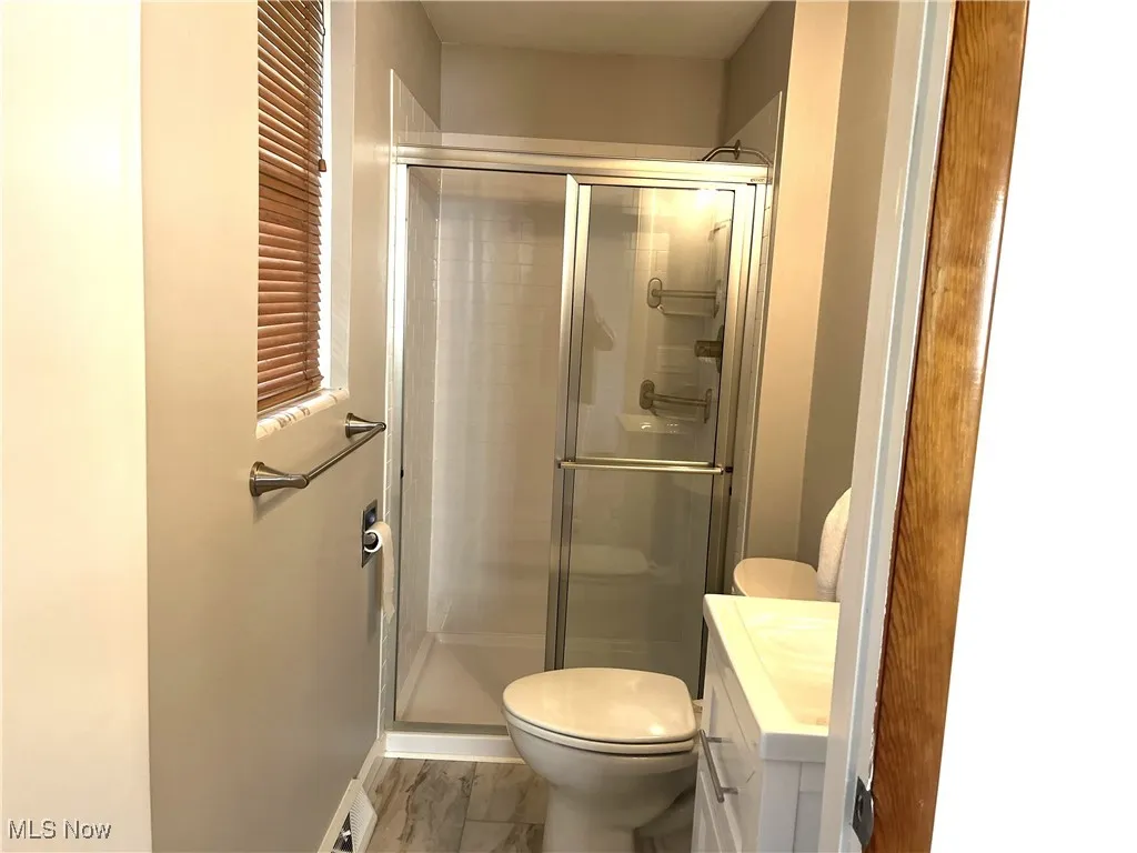 Full bathroom featuring a shower stall, vanity, and marble finish floors