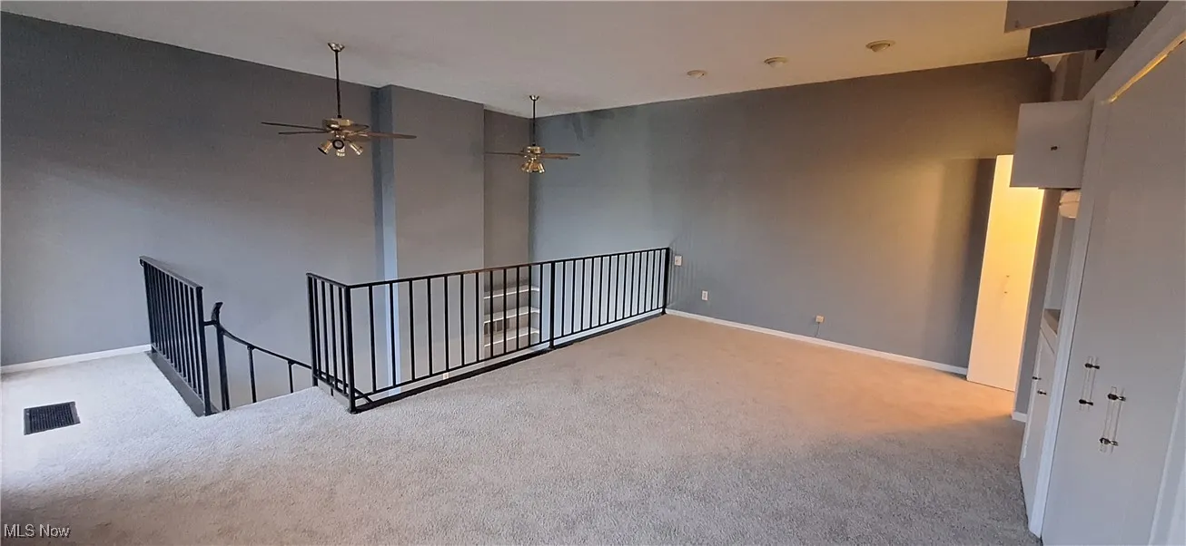 Carpeted empty room featuring a ceiling fan and baseboards