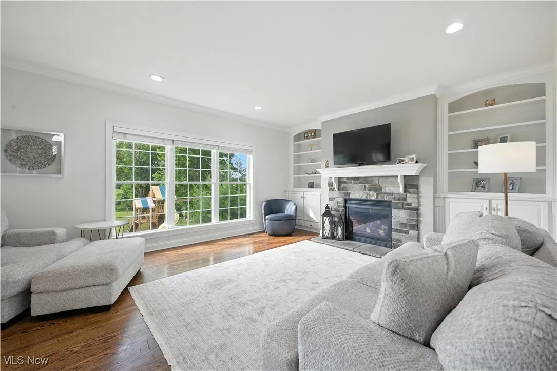 Living area with crown molding, a fireplace, recessed lighting, built in features, and dark wood-type flooring