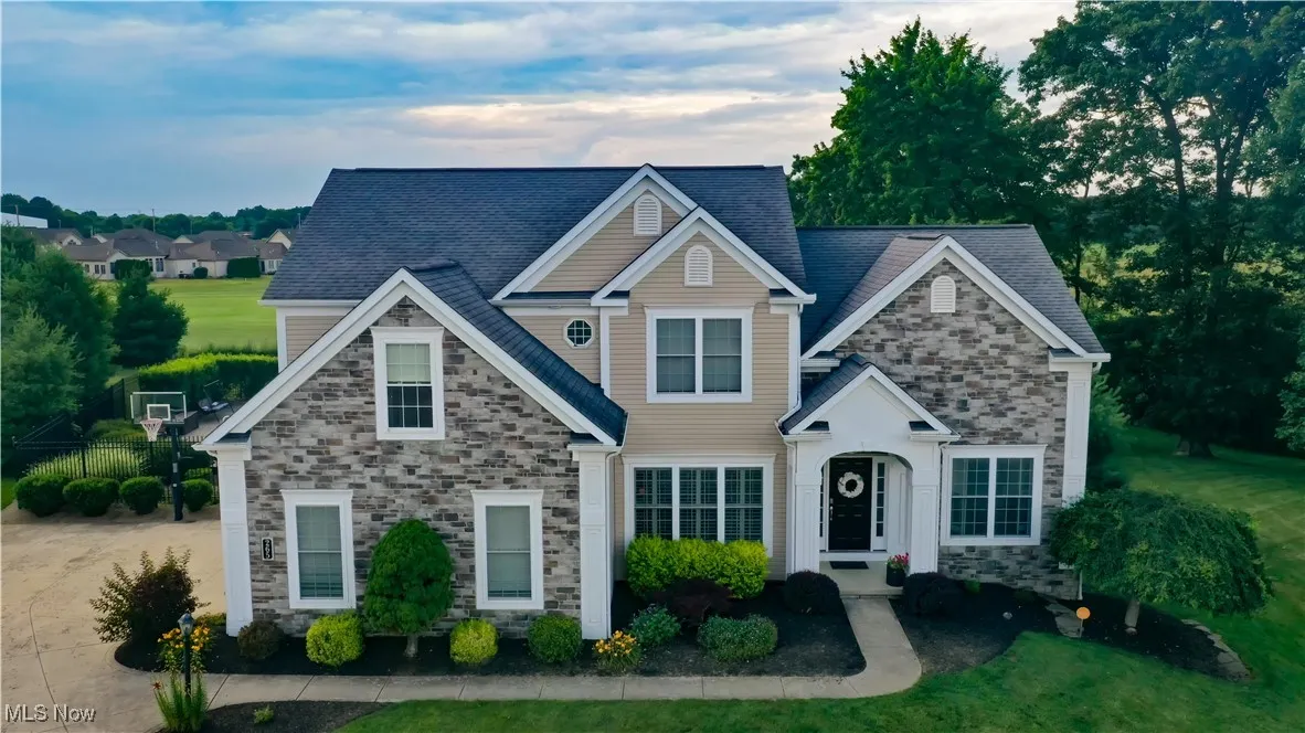 Traditional-style home with stone siding and a front lawn