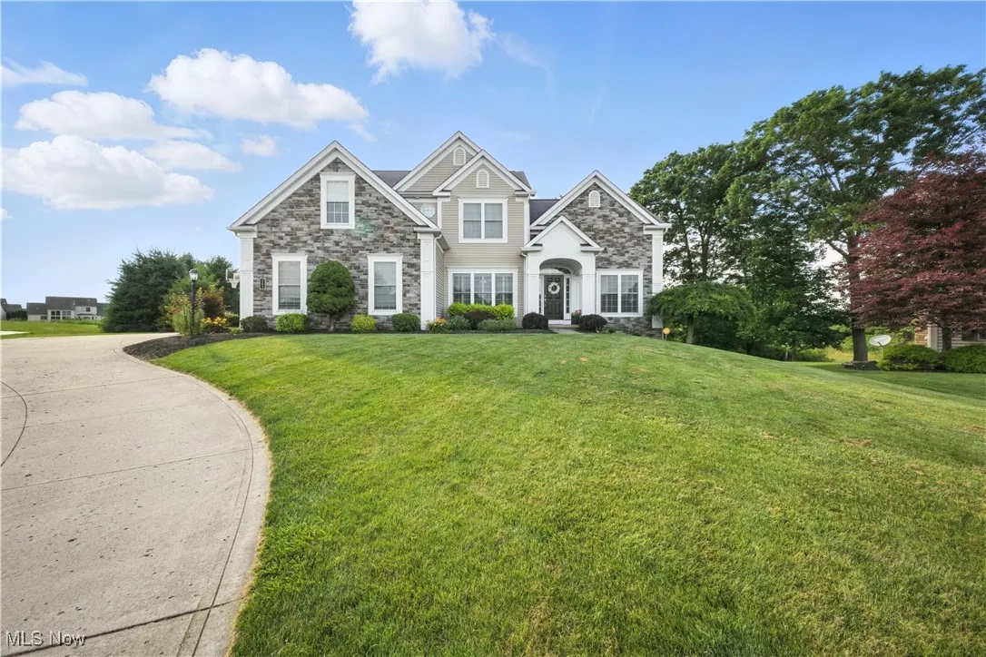 Traditional home with stone siding and a front yard