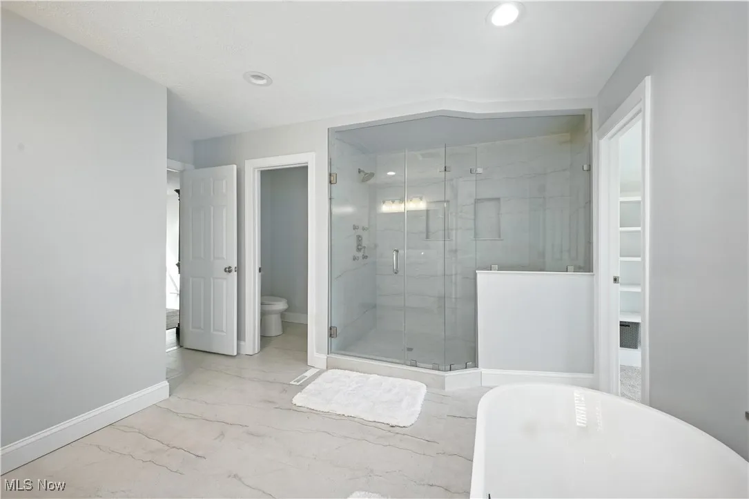 Full bathroom featuring marble finish flooring, a freestanding bath, a stall shower, recessed lighting, and a spacious closet