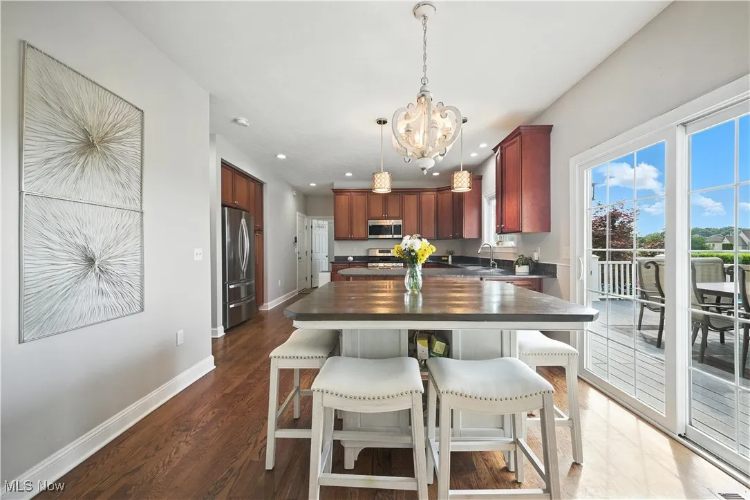 Kitchen with appliances with stainless steel finishes, a chandelier, recessed lighting, wooden counters, and dark wood-style floors