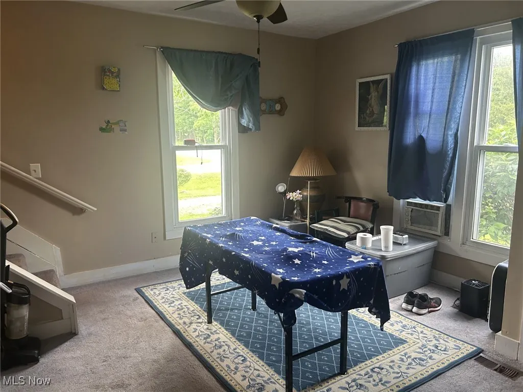 Carpeted office with healthy amount of natural light, cooling unit, and ceiling fan
