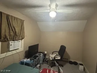 Bedroom with a textured ceiling, vaulted ceiling, ceiling fan, carpet flooring, and cooling unit