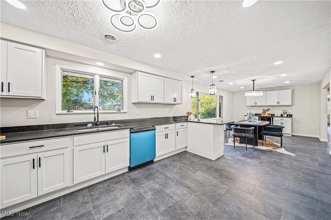 Kitchen featuring a textured ceiling, sink, decorative light fixtures, dishwasher, and white cabinetry
