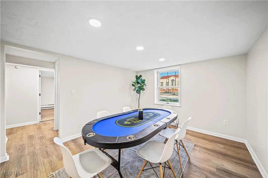 Dining area featuring light hardwood / wood-style flooring, a baseboard radiator, and a textured ceiling