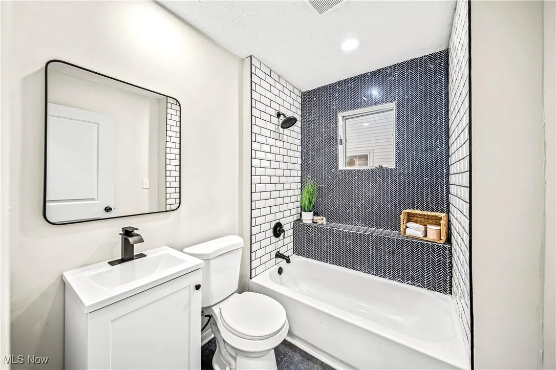 Full bathroom featuring vanity, toilet, tiled shower / bath, and a textured ceiling