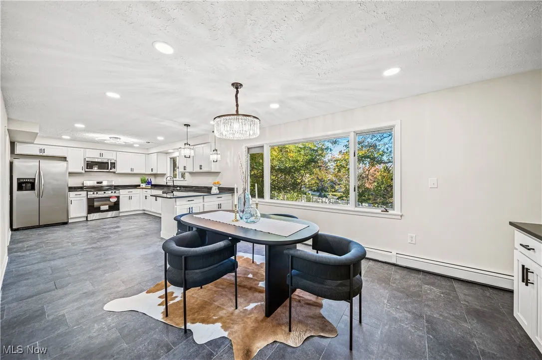 Dining room featuring a chandelier, sink, a baseboard heating unit, and a textured ceiling