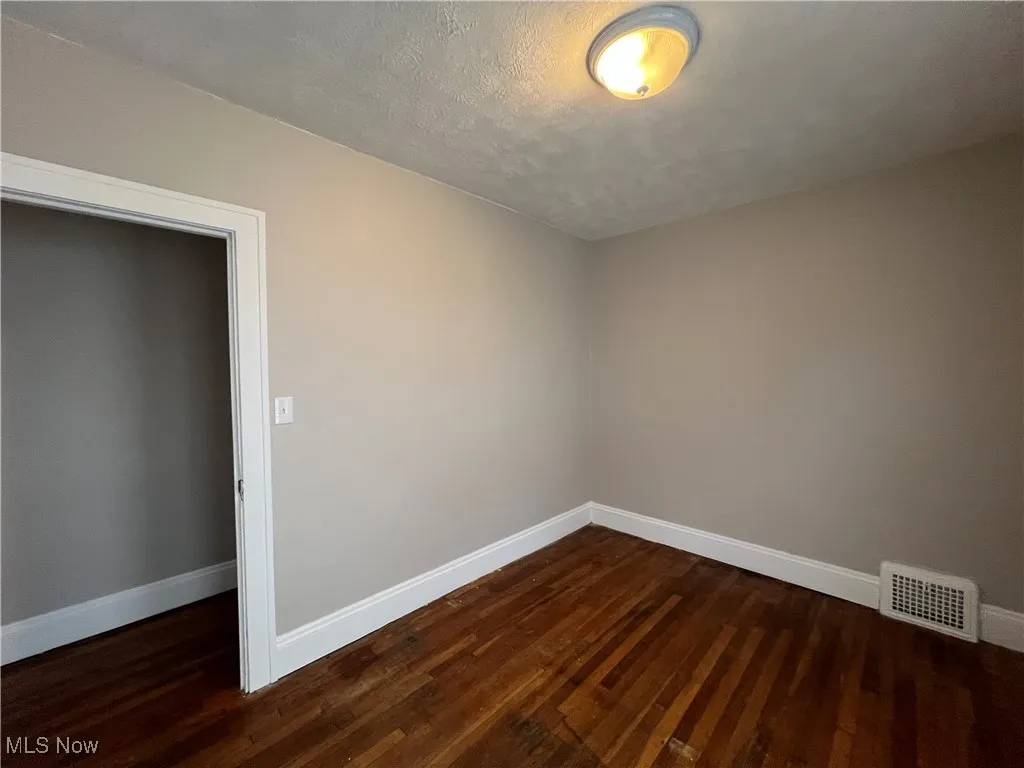 Spare room with dark wood-style flooring and a textured ceiling