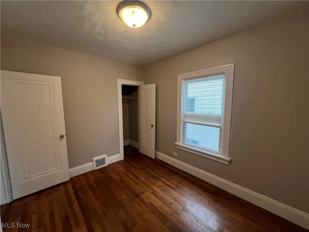 Unfurnished bedroom featuring a closet and dark wood-type flooring