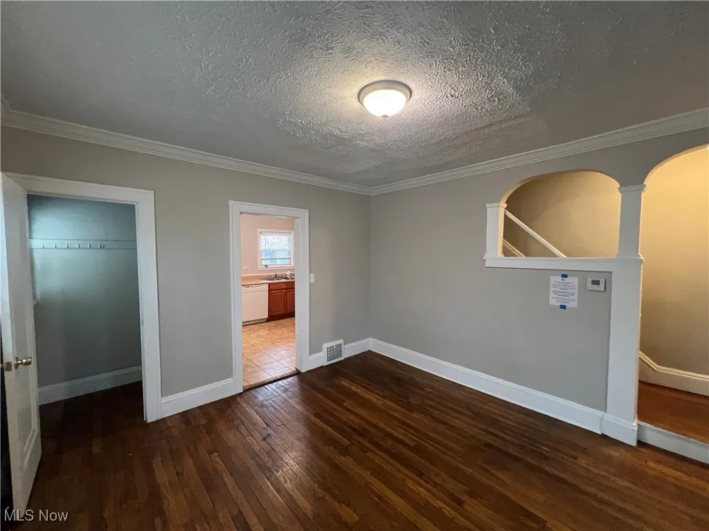 Unfurnished bedroom featuring hardwood / wood-style floors, crown molding, a textured ceiling, and a closet