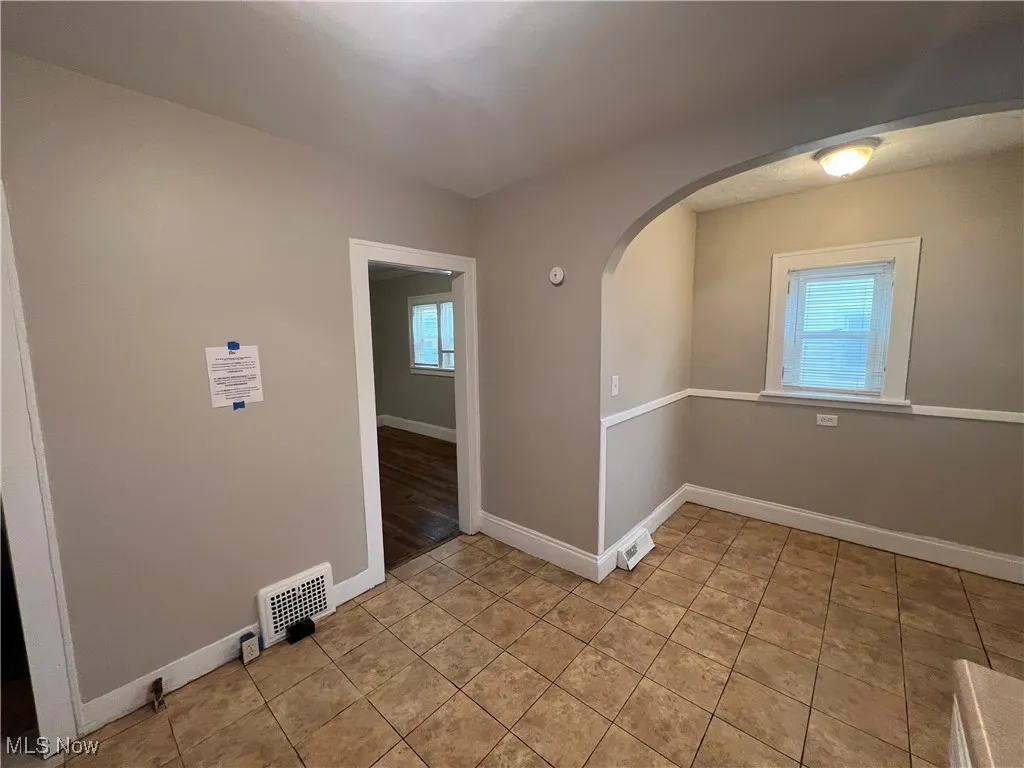 Empty room featuring arched walkways and light tile patterned floors