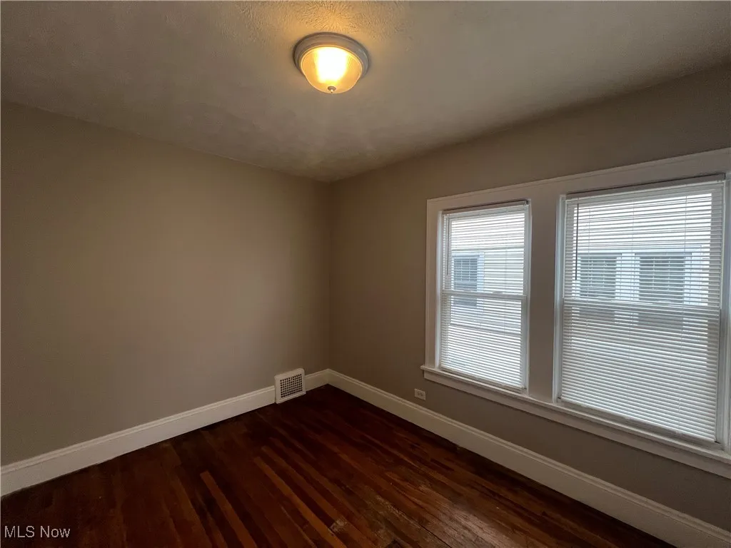 Empty room featuring baseboards and dark wood-style flooring