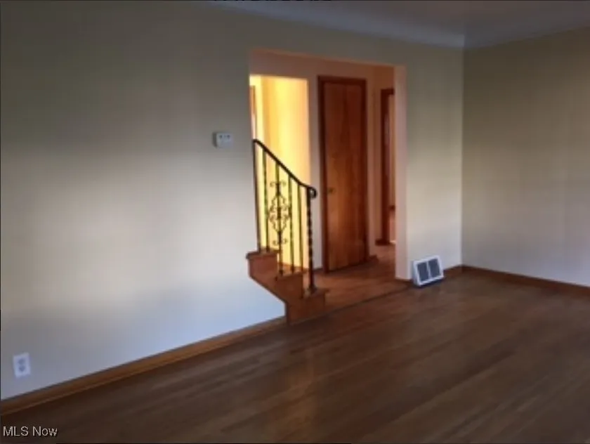 Unfurnished room with dark wood-style flooring and baseboards