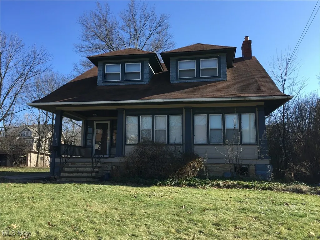 View of front of house featuring covered porch, a chimney, and a front lawn