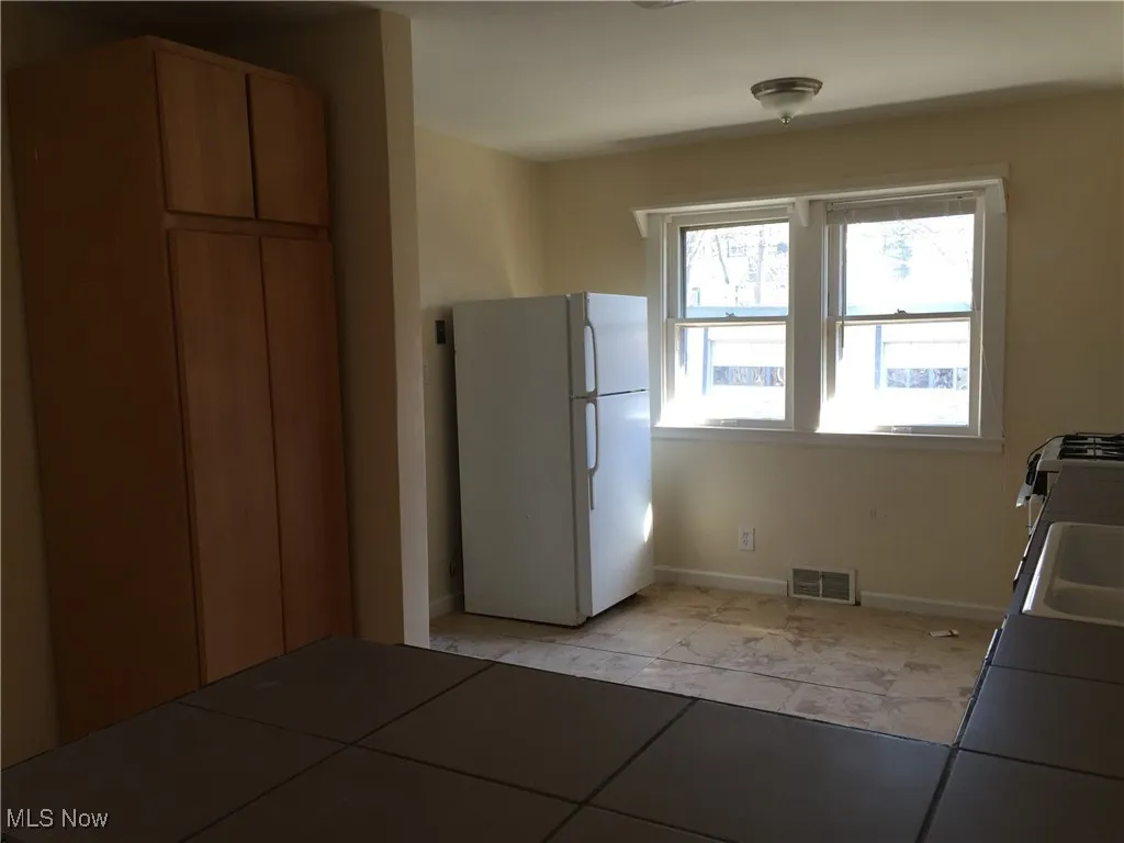 Kitchen with freestanding refrigerator and light tile patterned flooring