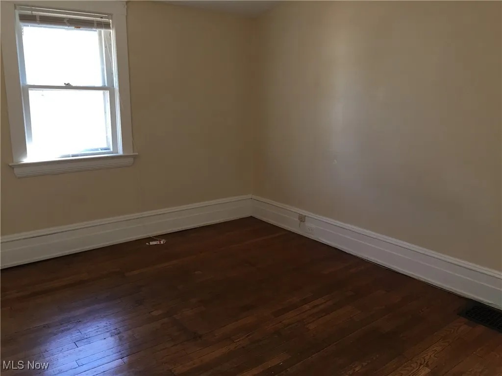 Unfurnished room featuring dark wood-style flooring and baseboards