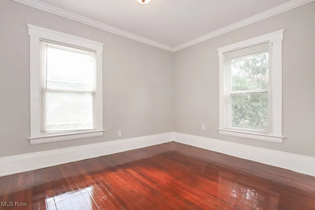 Unfurnished room featuring plenty of natural light, dark wood-type flooring, and ornamental molding