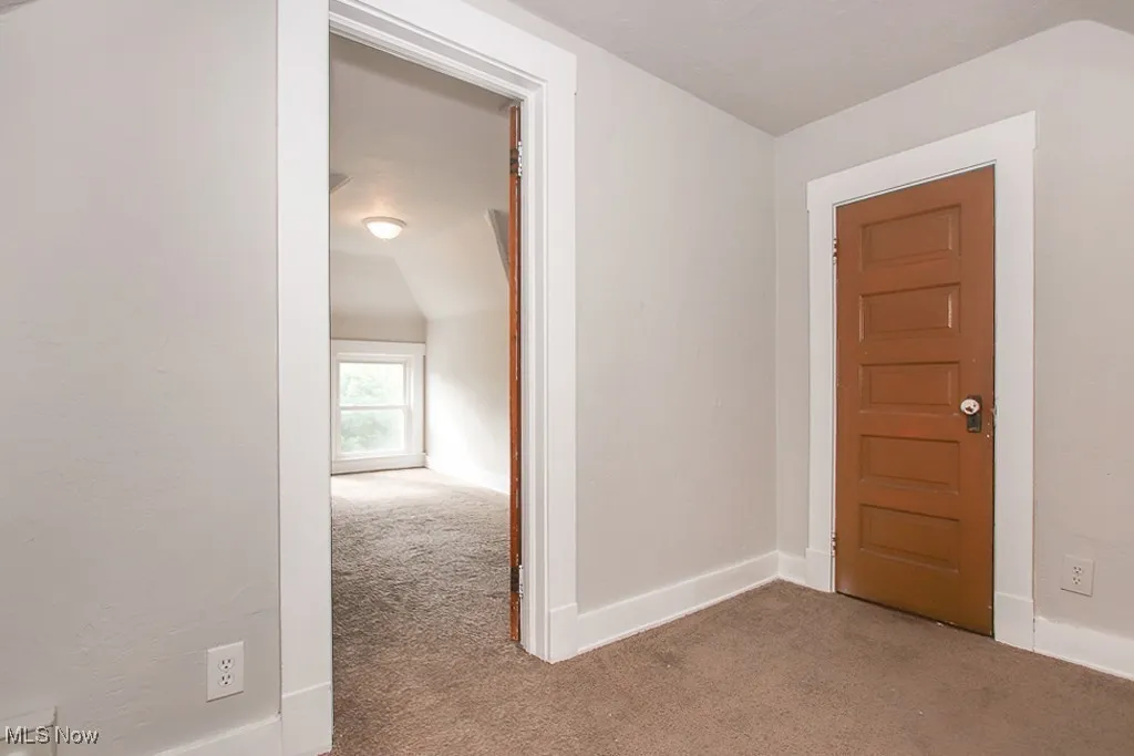 Hall with carpet floors and vaulted ceiling