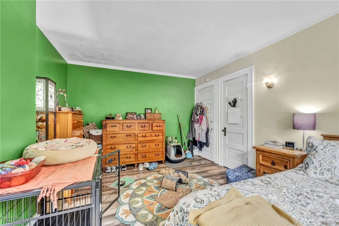 Bedroom with wood finished floors and ornamental molding