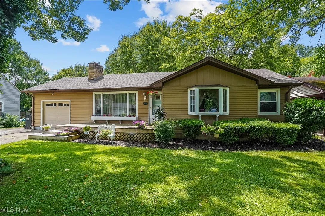 Single story home with an attached garage, a chimney, a front yard, and driveway