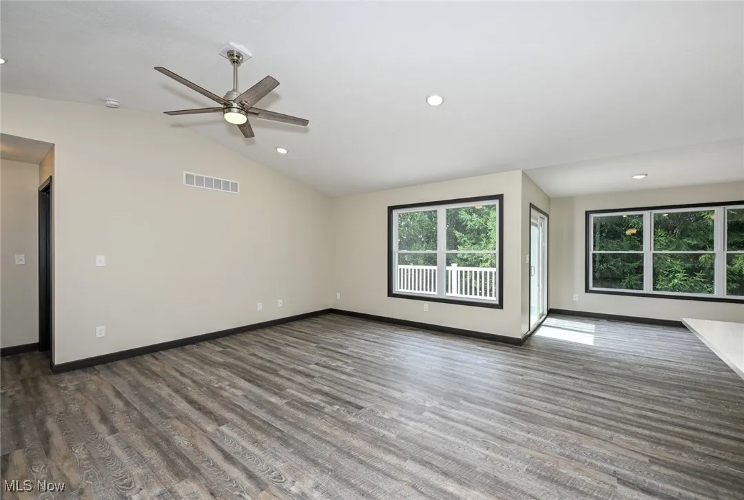 Great room with lofted ceiling, luxury engineered vinyl floors, recessed lighting, and a ceiling fan.