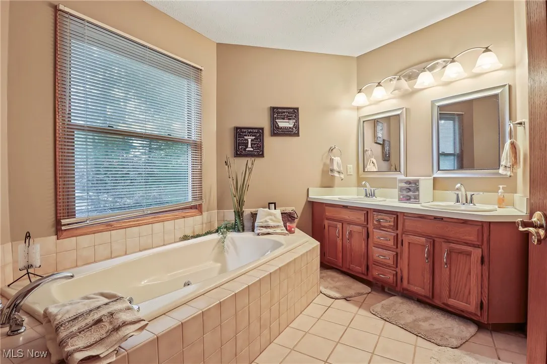 Bathroom featuring double vanity, a bath, and tile patterned floors