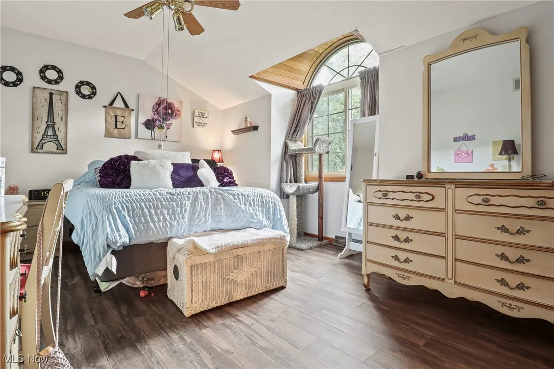 Bedroom with vaulted ceiling, wood finished floors, and ceiling fan