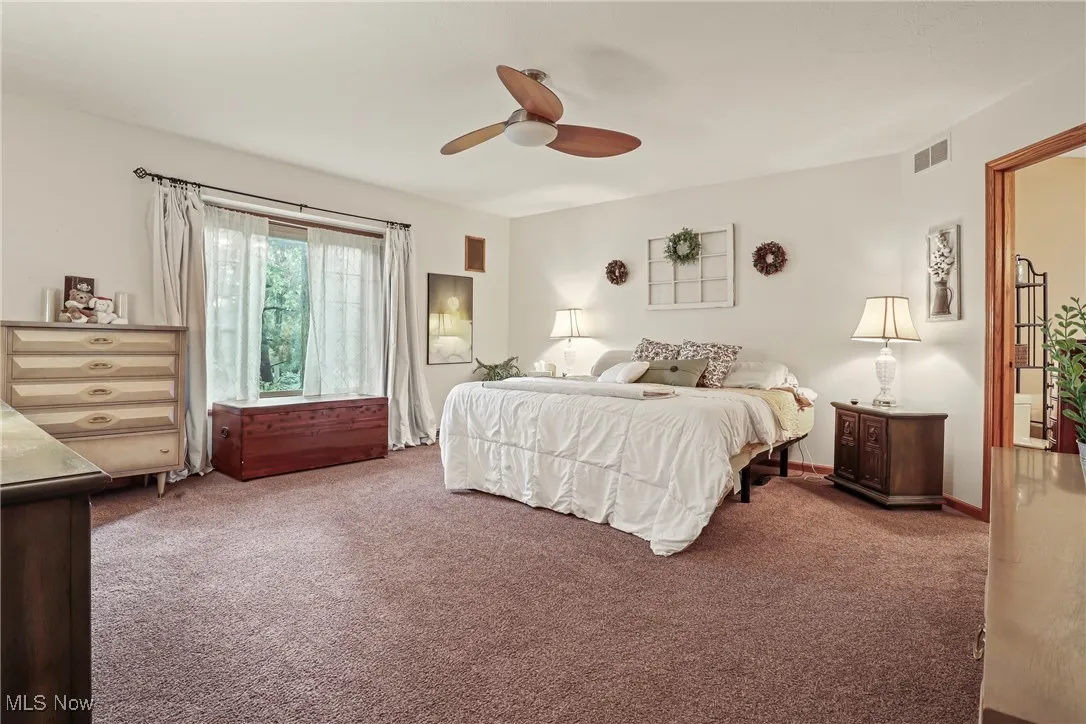 Carpeted bedroom featuring ceiling fan