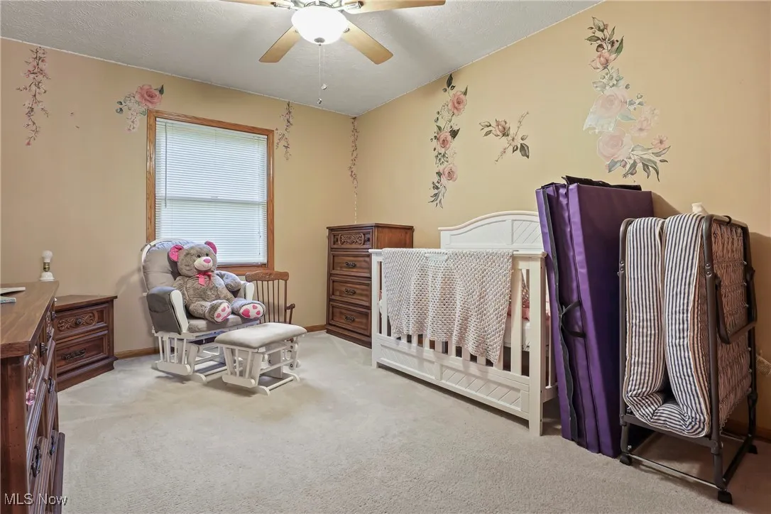 Carpeted bedroom with ceiling fan and baseboards
