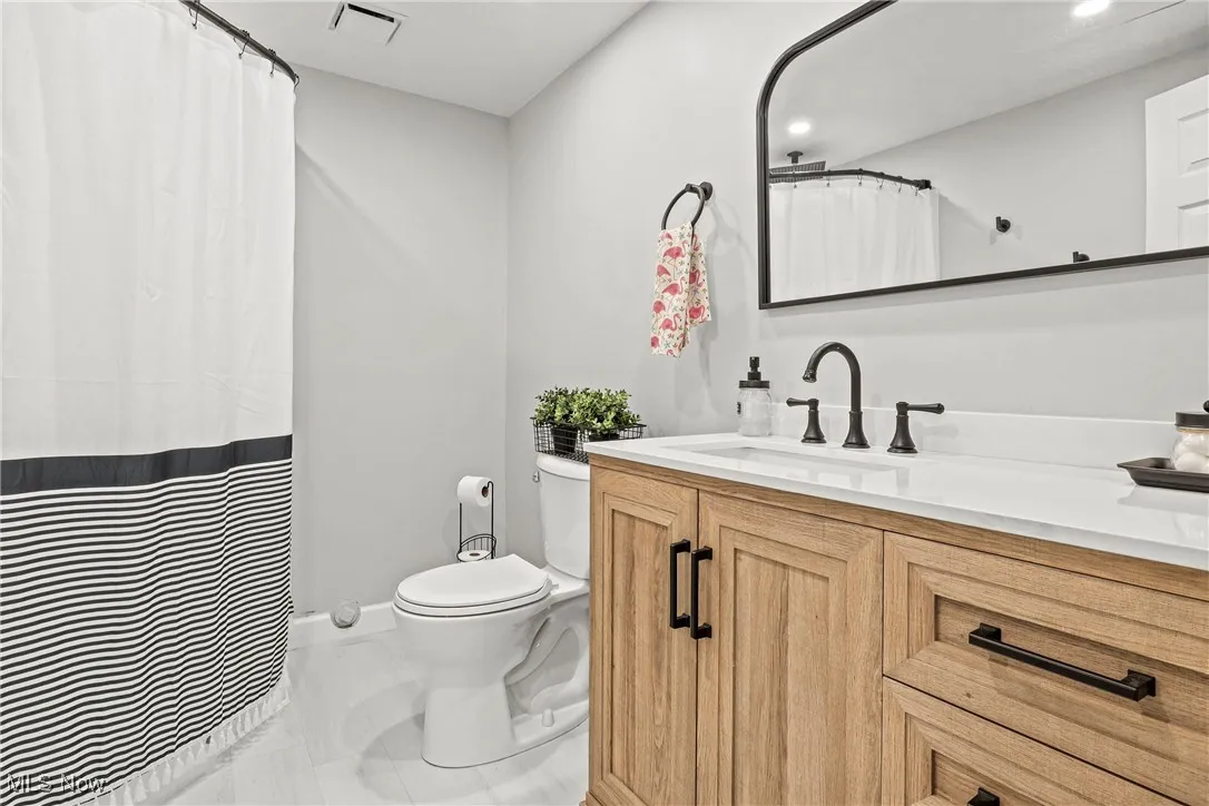 Full bath with vanity and curtained shower in basement.