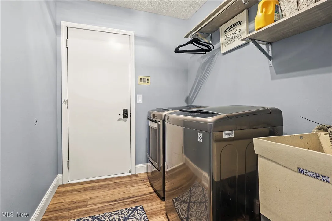 Laundry room with independent washer and dryer and light wood-type flooring