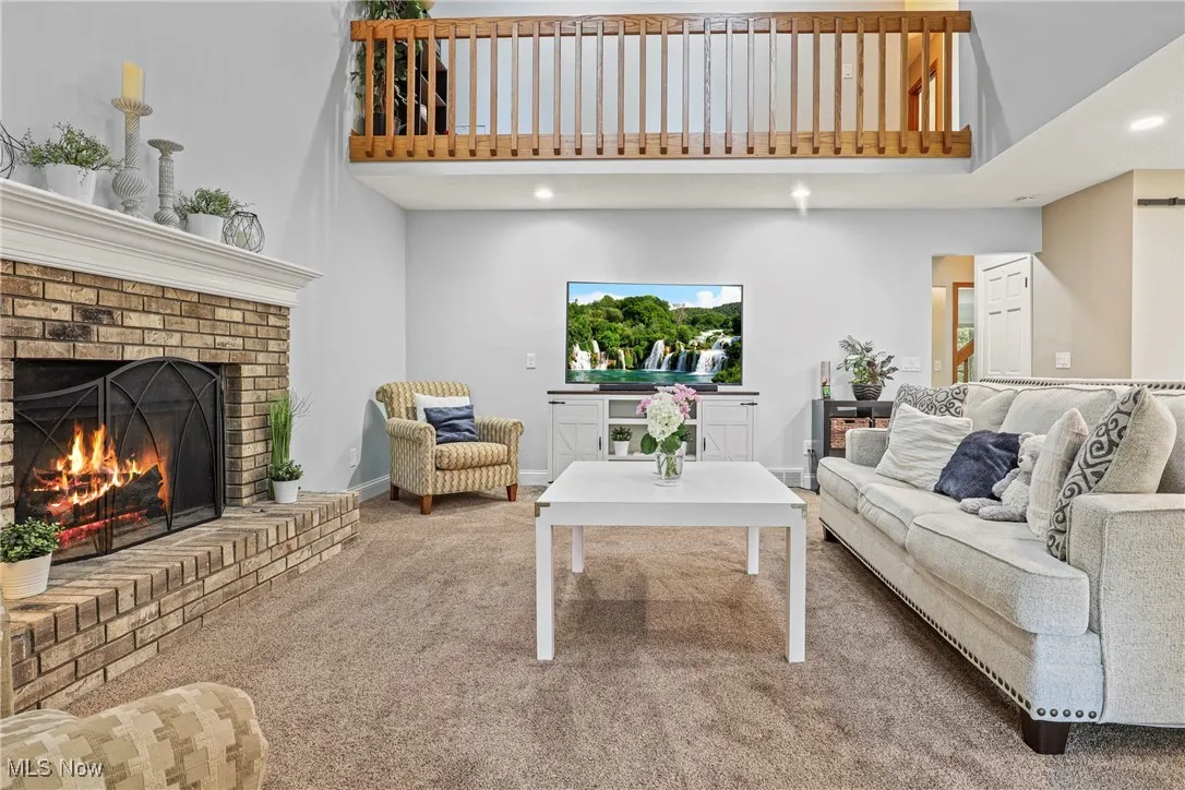 Carpeted living room featuring a brick fireplace, a high ceiling, and recessed lighting